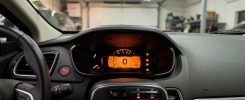 Vue rapprochée du tableau de bord d’une voiture Renault dans un garage réaliste, avec un voyant moteur orange allumé et une alerte liée à l’injection.
